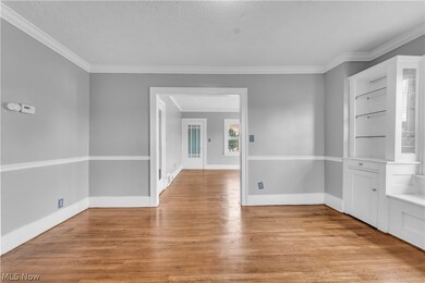 Empty room featuring crown molding, a textured ceiling, and light wood-type flooring