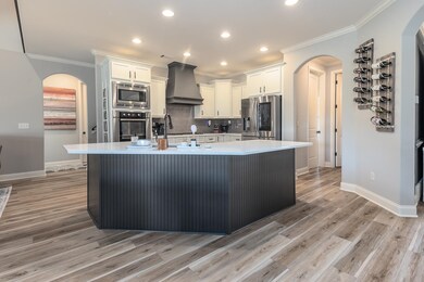Kitchen with white cabinetry, appliances with stai