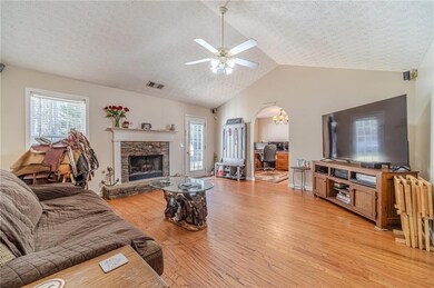 Living room with a textured ceiling, light wood-style floors, plenty of natural light, arched walkways, and ceiling fan