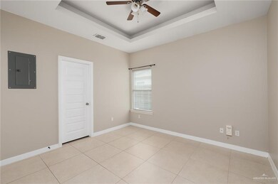 Unfurnished room with a ceiling fan, a tray ceiling, visible vents, and electric panel