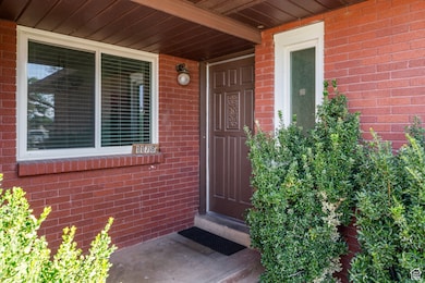View of exterior entry featuring covered porch and brick siding