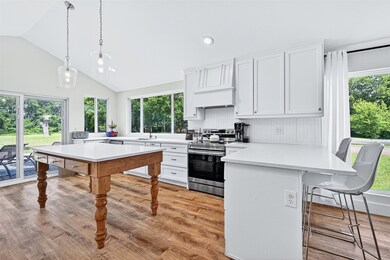 Kitchen with electric range, a peninsula, light countertops, a breakfast bar area, and high vaulted ceiling
