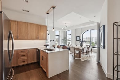 Kitchen with a peninsula, visible vents, appliances with stainless steel finishes, a sink, and dark wood-style floors