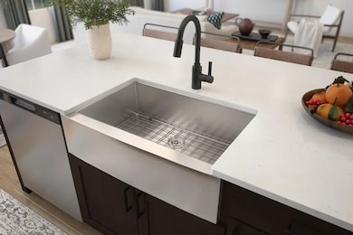 Stainless steel apron-front sink with matte black faucet