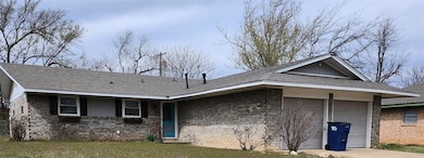 Single story home with a garage, brick siding, roo