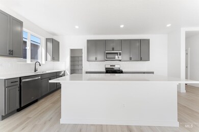 Kitchen featuring gray cabinetry, tasteful backsplash, a center island, stainless steel appliances, and light wood-style flooring