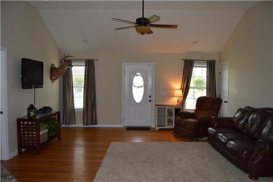 Great room features a vaulted ceiling and hardwood flooring.