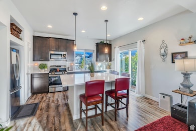 Kitchen featuring dark brown cabinetry, appliances with stainless steel finishes, a center island, a kitchen bar, and recessed lighting