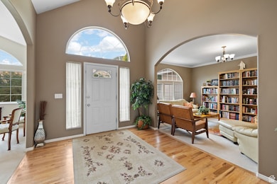 Entryway with a chandelier, arched walkways, light wood finished floors, and a high ceiling