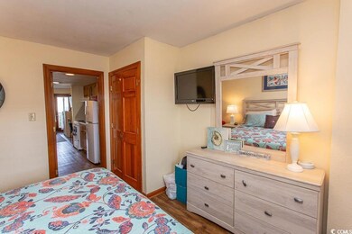 Bedroom with white fridge and dark hardwood / wood