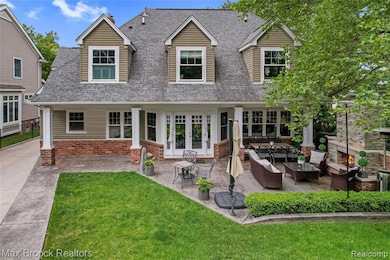 Back of house featuring an outdoor living space with a fireplace, a shingled roof, a patio, and brick siding