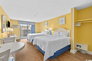 Bedroom featuring access to outside, a textured ceiling, wood finished floors, and a wall mounted AC
