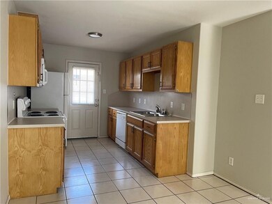 Kitchen with a sink, white appliances, light tile patterned floors, light countertops, and brown cabinetry