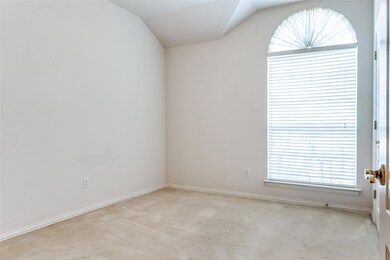 Empty room with light colored carpet and vaulted c