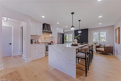 Kitchen with white cabinets, custom range hood, li