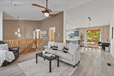Living area with light wood finished floors, a textured ceiling, a ceiling fan, and high vaulted ceiling