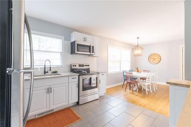 Kitchen featuring stainless steel appliances, healthy amount of natural light, white cabinetry, and decorative backsplash