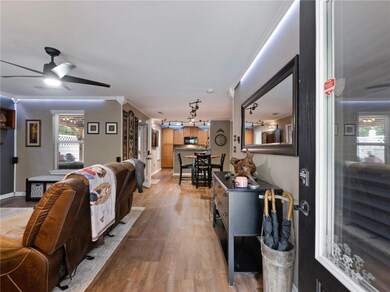 Living area featuring light wood-style floors, a ceiling fan, and baseboards
