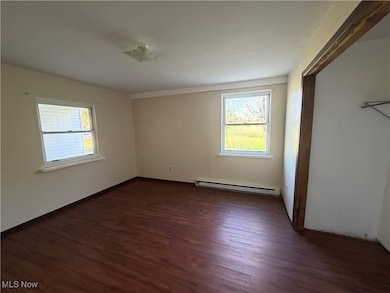 Main Floor Unfurnished bedroom featuring dark wood-style floors, multiple windows, and baseboard heating