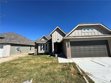 View of front of home featuring board and batten siding, brick siding, driveway, and a front lawn