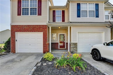 View of property featuring a garage, concrete driveway, and brick siding