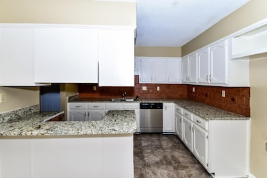 Kitchen featuring a peninsula, white cabinets, dishwasher, a textured ceiling, and backsplash