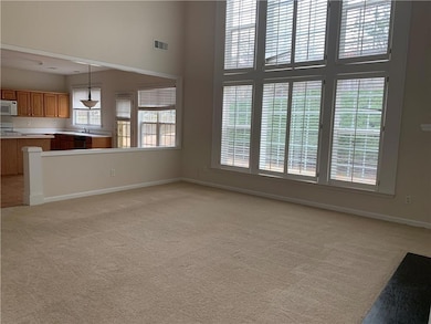 Unfurnished living room with light carpet and a high ceiling