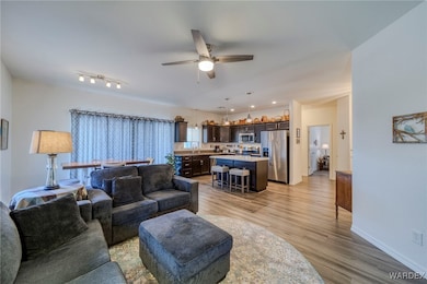 Living room with a ceiling fan, light wood-type fl