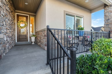 Doorway to property featuring stucco siding, stone siding, and a balcony