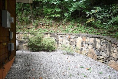 Gravel area and rock wall winds around to the rear of the home