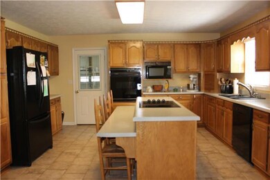 The kitchen with a large island and cook top and abundant cabinetry with plenty of storage. Nice new granite composite sink and faucet. 18x15 / Eat-In