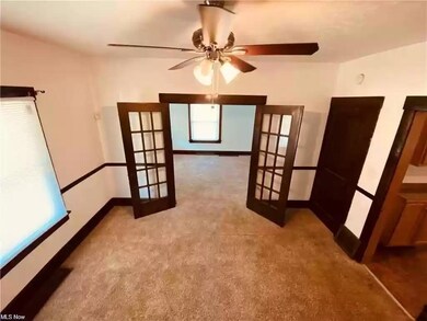 Spare room featuring ceiling fan, light colored carpet, and french doors
