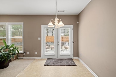 Doorway with a chandelier, french doors, light tile patterned floors, and baseboards