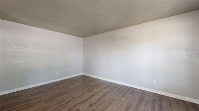 Empty room featuring dark wood-style flooring and a textured ceiling