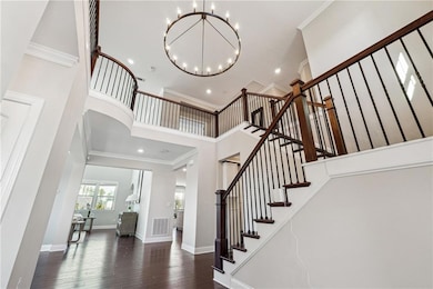 Staircase with a chandelier, crown molding, a towering ceiling, hardwood / wood-style flooring, and recessed lighting