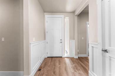 Entrance foyer with light wood-type flooring and a wainscoted wall