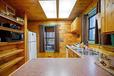 Kitchen with white appliances, wood ceiling, sink,