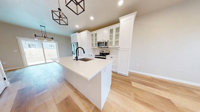 Kitchen featuring decorative light fixtures, glass insert cabinets, an island with sink, recessed lighting, and stainless steel appliances