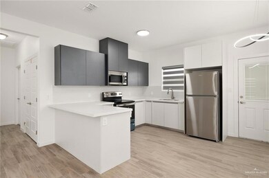 Kitchen featuring appliances with stainless steel finishes, white cabinets, sink, light hardwood / wood-style floors, and gray cabinetry