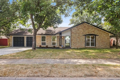 View of front of home featuring concrete driveway, brick siding, an attached garage, and a front yard