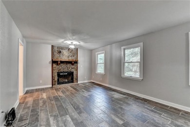Unfurnished living room with a stone fireplace and wood finish floors