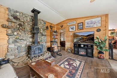 Living area featuring wood walls, lofted ceiling, a wood stove, wood finished floors, and a warm lit fireplace