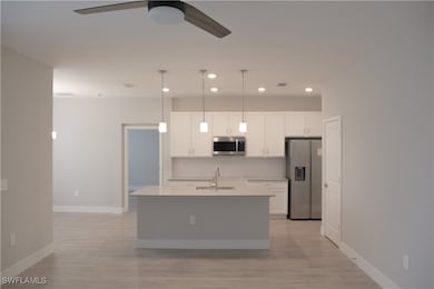 Kitchen with a sink, white cabinets, a ceiling fan
