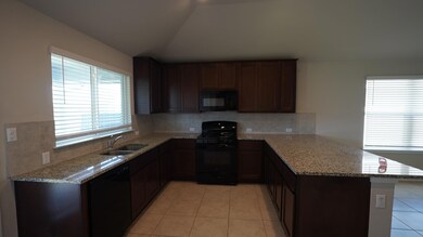 Kitchen featuring light stone counters, black appliances, a peninsula, light tile patterned floors, and lofted ceiling