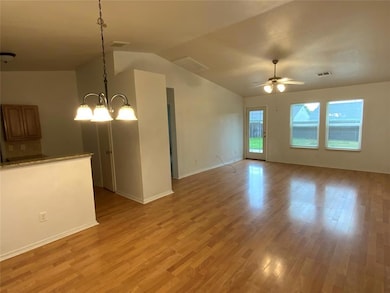 Unfurnished living room featuring vaulted ceiling, light wood-type flooring, a ceiling fan, baseboards, and a chandelier
