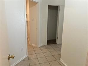 Hall with baseboards and light tile patterned flo
