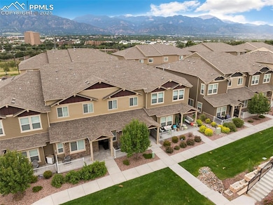 View of front facade with stone siding, a residential view, a mountain view, a shingled roof, and a patio area