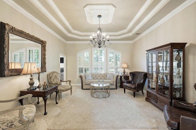 Sitting room featuring a raised ceiling, a chande
