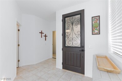 Foyer entrance with baseboards and light tile patt
