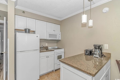 Kitchen featuring white appliances, crown molding, white cabinets, a textured ceiling, and pendant lighting